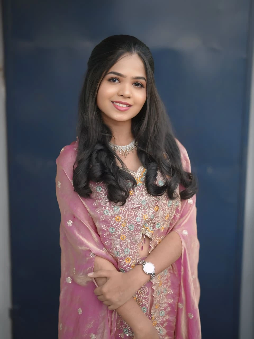Bride in an embellished pink lehenga outfit with styled soft wavy hair posing indoors
